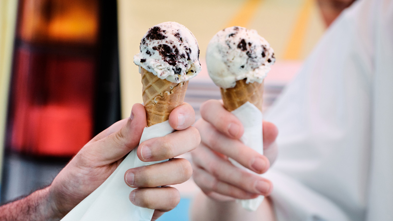 Two hands holding scoops of ice cream in cones at the Summer on the Square festival 