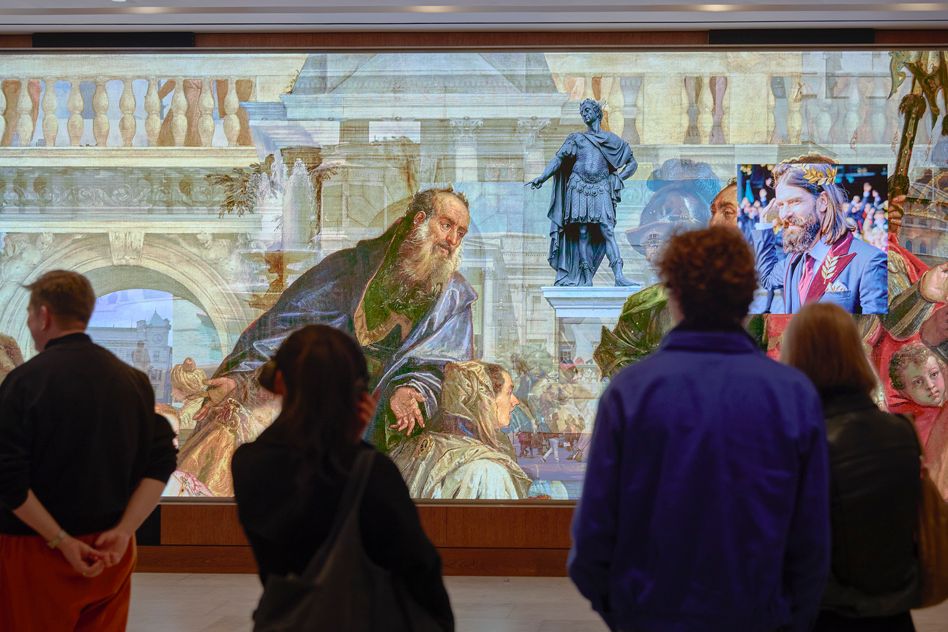 Visitors watch the Community Connector film on the Big Screen in the Sainsbury Wing in the National Gallery.