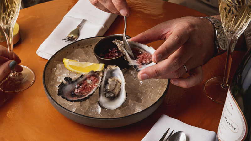 Oysters in a bowl of ice with a lemon wedge 
