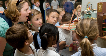 A teacher and children looking at an exhibit in a glass case