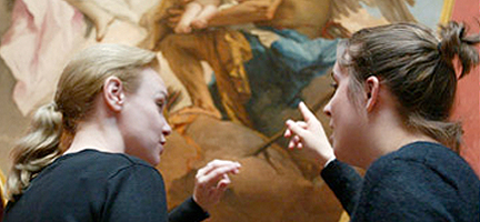 Two women having an animated discussion about a painting